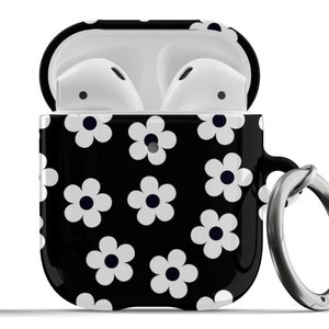 May include: Black Airpods case with a white daisy print and a silver metal keychain ring.