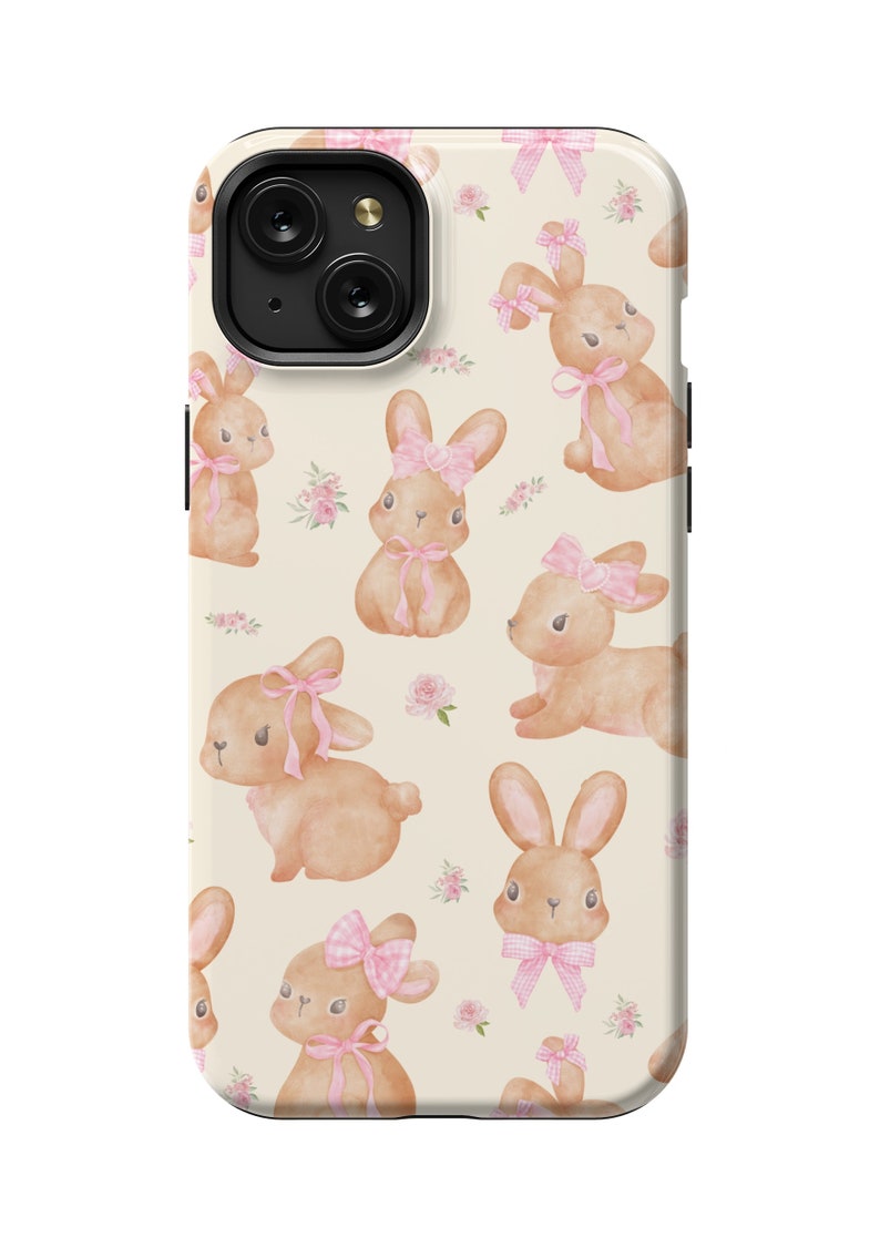 May include: A cream-colored phone case with a repeating pattern of brown bunnies wearing pink bows and pink flowers. The case has a black camera cutout.