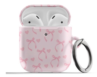 May include: A pink silicone case for Apple AirPods with a pink bow and heart pattern. The case has a silver metal carabiner attached.