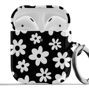 Könnte beinhalten: Eine schwarze und weiße Hülle mit Blumenmuster für Apple AirPods mit einem silbernen Metallring.