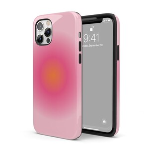 K&ouml;nnte beinhalten: Eine rosa Handyh&uuml;lle mit einem Farbverlauf-Design, das einen gelben und orangen Kreis in der Mitte zeigt. Die H&uuml;lle wird mit einer schwarzen Handyh&uuml;lle gezeigt, deren Bildschirm die Uhrzeit 9:41 und das Datum Dienstag, 10. September anzeigt.