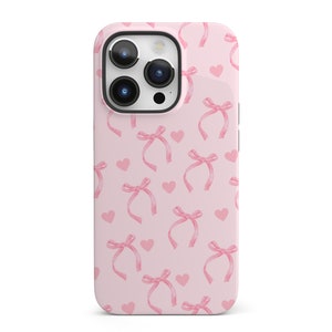 May include: A pink phone case with a pattern of pink bows and hearts.