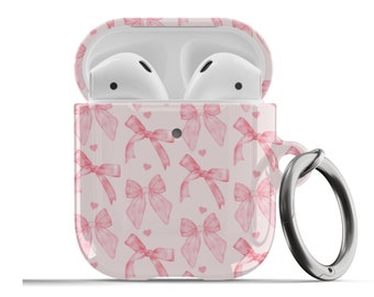 May include: A pink and white Airpods case with a pink bow pattern and a silver metal ring attached.