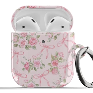 Puede incluir: Una funda para Apple AirPods con estampado floral rosa y blanco y un mosquetón de metal plateado.
