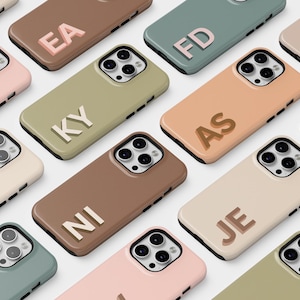 May include: Assortment of phone cases in various colors with different letter combinations. The cases are made of a soft, textured material and feature a raised letter design.