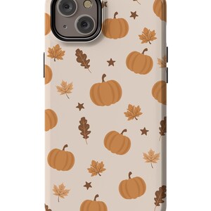 Puede incluir: Una funda de tel&eacute;fono beige con un patr&oacute;n de calabazas naranjas, hojas marrones y estrellas marrones.
