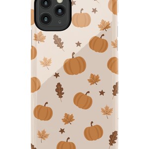 Puede incluir: Una funda de tel&eacute;fono beige con un patr&oacute;n de calabazas naranjas y hojas marrones. La funda tiene un recorte para una lente de c&aacute;mara.