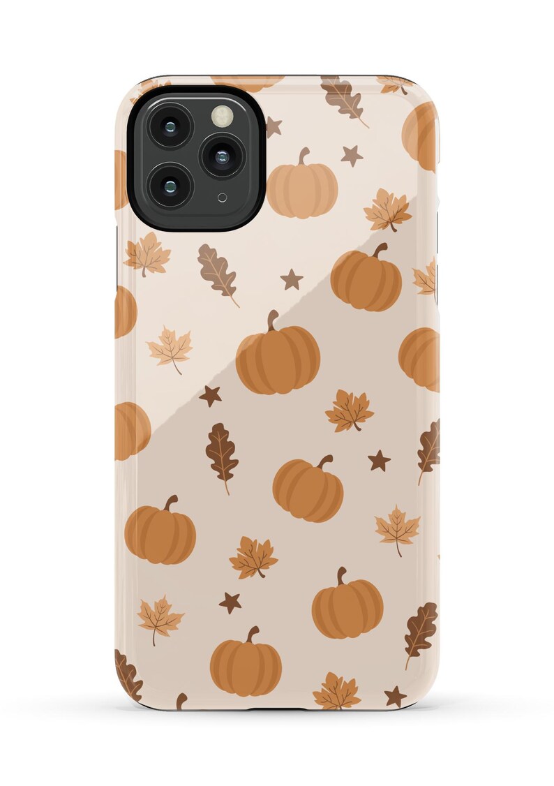 Puede incluir: Una funda de tel&eacute;fono beige con un patr&oacute;n de calabazas naranjas y hojas marrones. La funda tiene un recorte para una lente de c&aacute;mara.