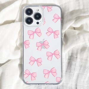 May include: A clear phone case with a pink bow pattern. The case is designed for an iPhone with a triple lens camera.