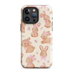 May include: A phone case with a cream background and a repeating pattern of brown bunnies wearing pink bows. The bunnies are surrounded by pink flowers.