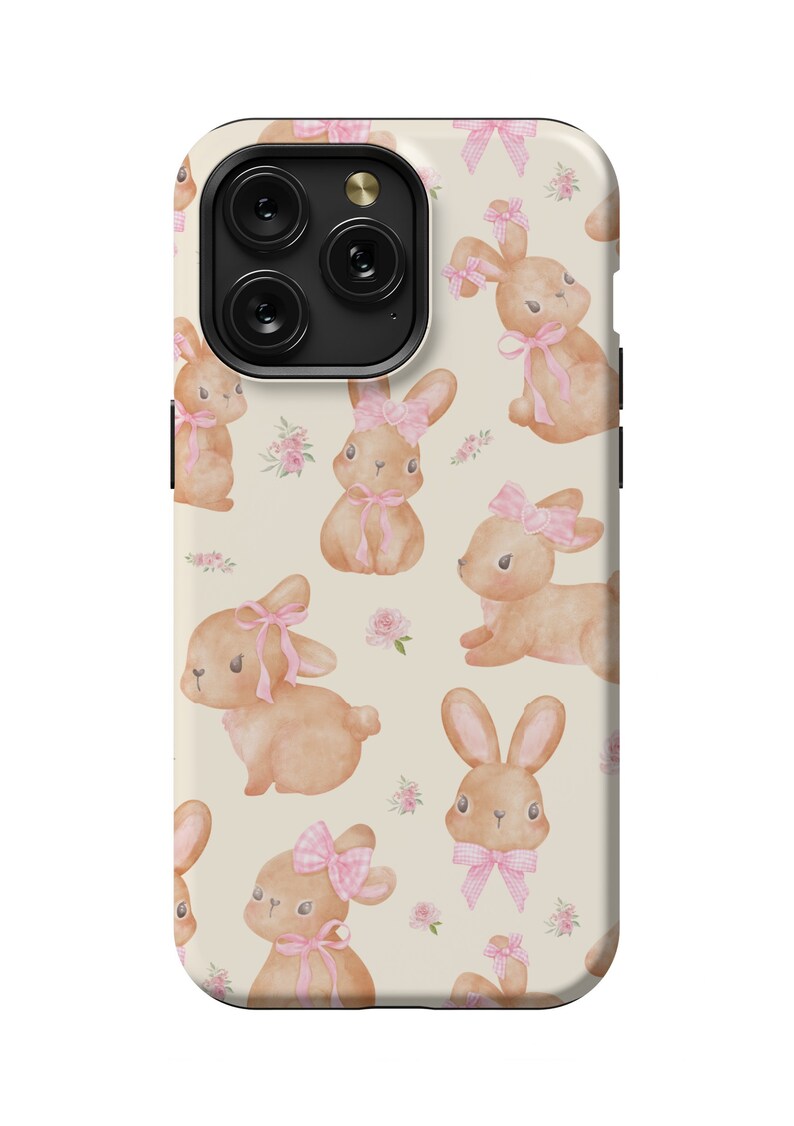 May include: A cream-colored phone case with a repeating pattern of brown bunnies wearing pink bows. The bunnies are surrounded by small pink flowers.