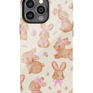 May include: A phone case with a pattern of brown bunnies wearing pink bows on a cream background.