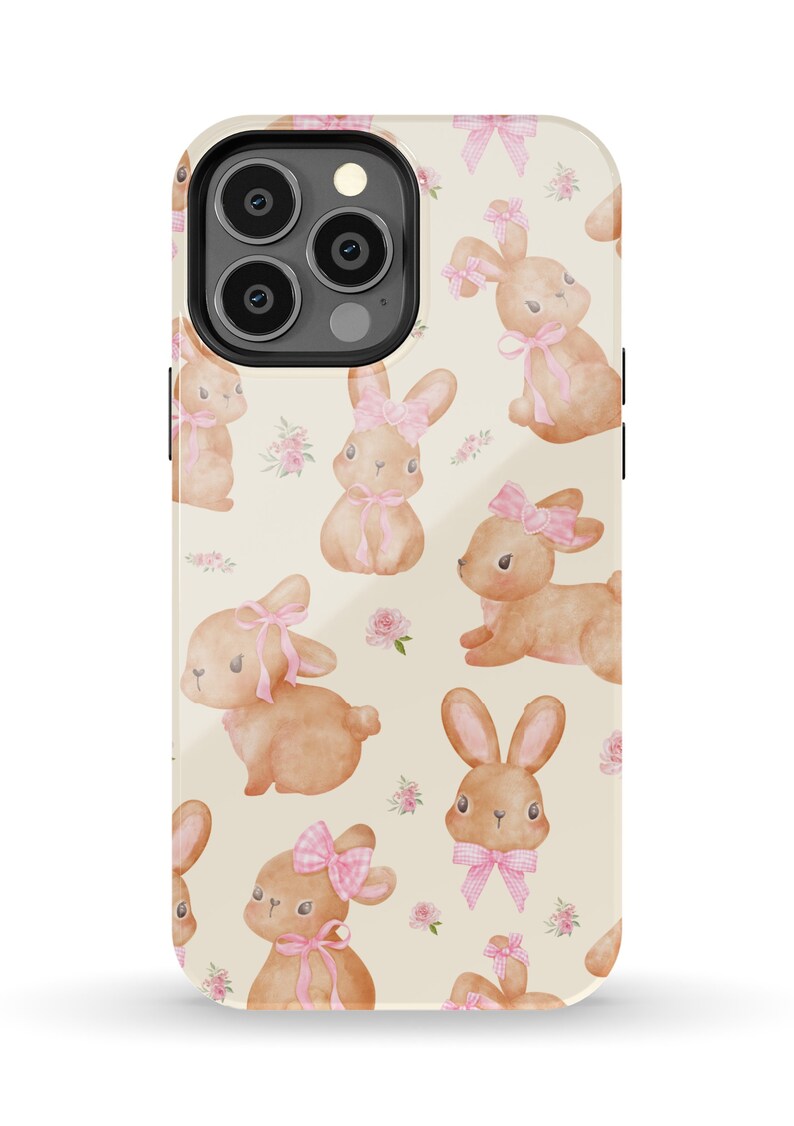 May include: A phone case with a pattern of brown bunnies wearing pink bows on a cream background.