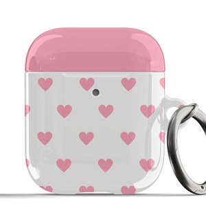 May include: A white and pink Airpods case with a pink heart pattern and a silver metal keychain ring.