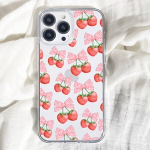 May include: A clear phone case with a white background and a repeating pattern of pink bows and red cherries.