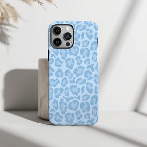 Pu&ograve; includere: Una custodia per telefono blu chiaro con un motivo a stampa leopardata.