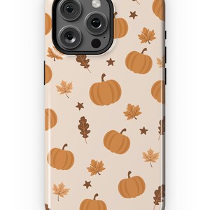 Puede incluir: Una funda de tel&eacute;fono beige con un patr&oacute;n de calabazas naranjas, hojas marrones y estrellas marrones.