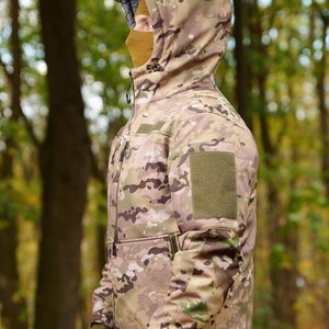 May include: A camouflage jacket with a hood and a green patch on the sleeve. The jacket is made of a soft, water-resistant material and is perfect for outdoor activities.