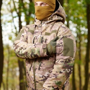 May include: A camouflage jacket with a hood and a brown balaclava. The jacket has multiple pockets and a zipper closure. The jacket is made of a soft, comfortable material.