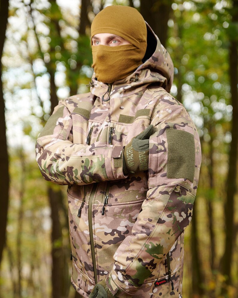 May include: A camouflage jacket with a hood and a brown balaclava. The jacket has multiple pockets and a zipper closure. The jacket is made of a soft, comfortable material.