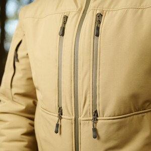 May include: A tan jacket with two zippered pockets on the front. The zippers have silver pulls.