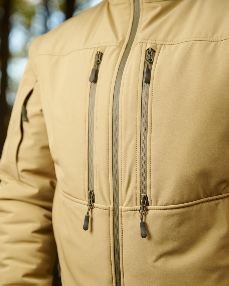 May include: A tan jacket with two zippered pockets on the front. The zippers have silver pulls.