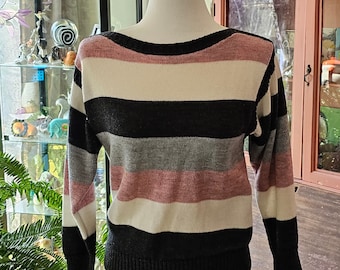 May include: A striped sweater with long sleeves in black, white, gray, and pink.