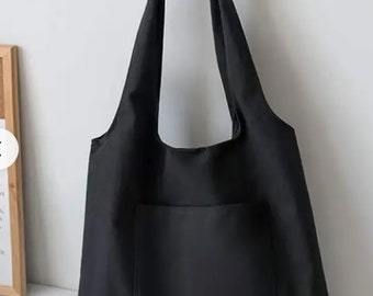 May include: A black tote bag with a single pocket on the front. The bag has two straps.