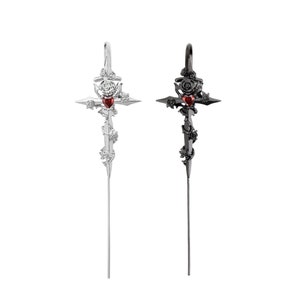 May include: Two silver and black cross earrings with a red heart and rose details.