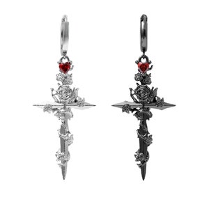 May include: A pair of black and silver earrings with a cross design. Each earring features a sword with roses and a red heart at the top.