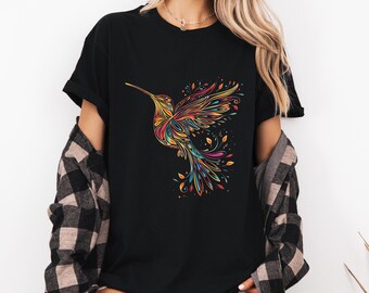 Puede incluir: Camiseta negra con un diseño de colibrí multicolor. El colibrí está representado con detalles intrincados y una gama de colores, incluyendo amarillo, naranja, rojo, azul y verde. La camiseta es de estilo casual, adecuada para el uso diario.
