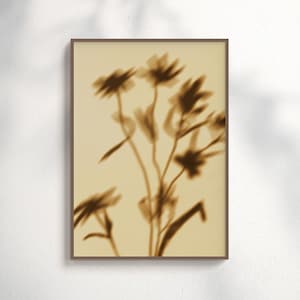 Könnte beinhalten: Ein gerahmter Sepia-Druck mit einem verschwommenen Bild von Blumen. Die Blumen haben lange Stiele und zarte Blütenblätter mit einer weichen, künstlerischen Ästhetik. Der Rahmen ist warmbraun und der Hintergrund hellbeige.