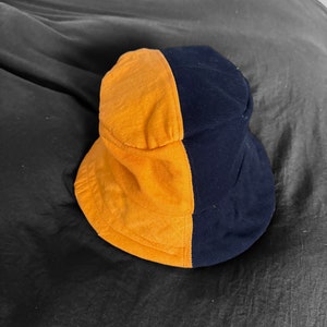 May include: A black and yellow bucket hat with a contrasting color design. The hat is made of a soft, comfortable fabric.