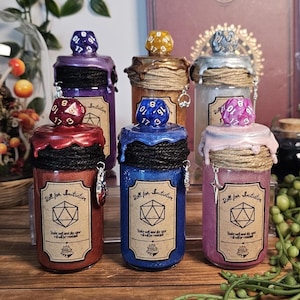 May include: Six decorative glass jars with colorful glitter and dice-shaped stoppers. Each jar has a label that reads "Roll for Initiative." The jars are in shades of red, blue, purple, gold, silver, and pink, with twine and charms.