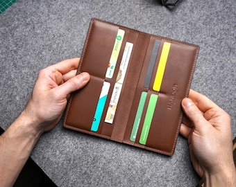 May include: A brown leather wallet with multiple card slots and a money clip. The wallet is open and has several cards inside. The brand name "HANDIOR" is embossed on the front of the wallet.