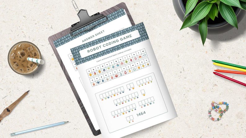 Pode incluir: Uma prancheta cont&eacute;m duas folhas de papel com o texto "ANSWER SHEET" e "ROBOT CODING GAME". O jogo ensina conceitos b&aacute;sicos de codifica&ccedil;&atilde;o com ilustra&ccedil;&otilde;es coloridas de rob&ocirc;s. Um copo de caf&eacute; gelado, l&aacute;pis e uma pulseira tamb&eacute;m s&atilde;o vis&iacute;veis.