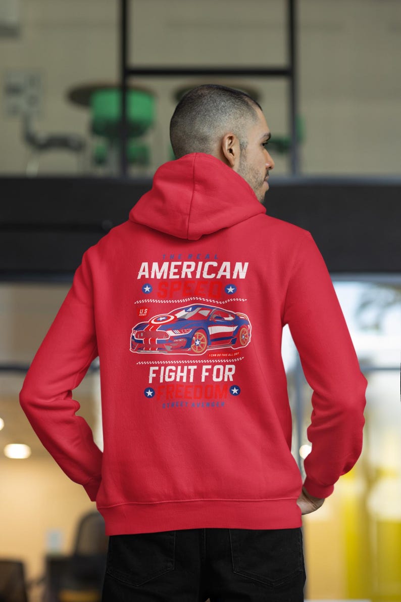 Op de afbeelding: Rode hoodie met een afbeelding op de rug met een blauwe en rode sportwagen, de tekst "AMERICAN SPEED" en "FIGHT FOR FREEDOM". De hoodie heeft een capuchon en lange mouwen.