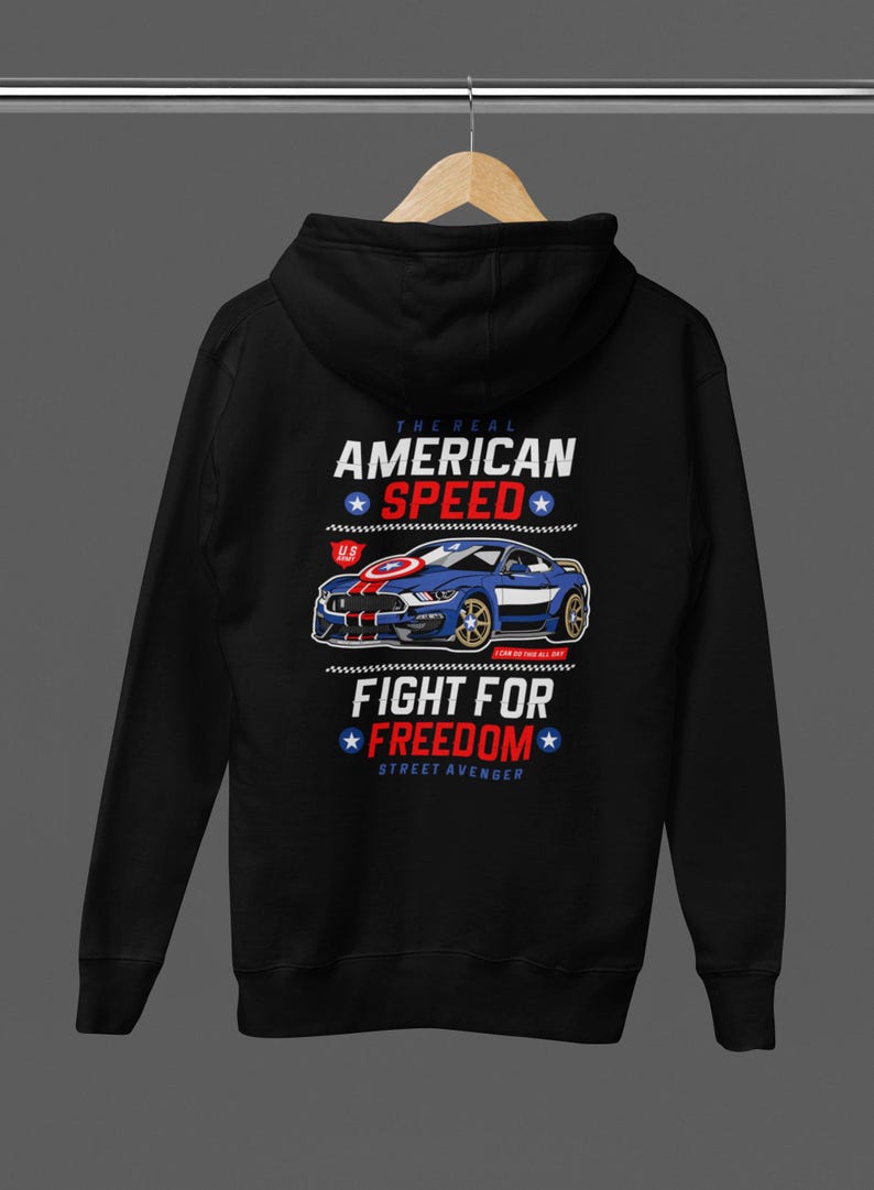 Op de afbeelding: Zwarte hoodie met een afbeelding van een blauwe sportwagen, rode en witte strepen en tekst. Het ontwerp bevat de zinnen "THE REAL AMERICAN SPEED" en "FIGHT FOR FREEDOM" met sterren, in een patriottische stijl.