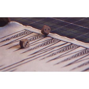 Puede incluir: Primer plano de un tablero de backgammon con dos dados de madera. El tablero tiene una superficie color crema con diseños geométricos negros y grises. Los dados son marrones con puntos negros, uno mostrando dos puntos y el otro tres.