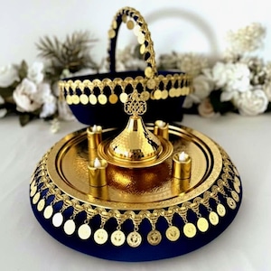 Pode incluir: Uma bandeja de servir decorativa dourada e azul marinho com uma cesta a condizer. A bandeja tem uma borda dourada com enfeites pendurados em forma de moeda. A bandeja contém um queimador de incenso dourado e quatro pequenos castiçais.