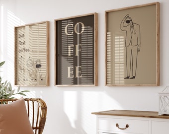 Pode incluir: Três ilustrações emolduradas em uma parede branca. As ilustrações são em preto e branco e apresentam um homem servindo café, a palavra "COFFEE" e um homem de terno. A parede é branca com um armário de madeira abaixo.