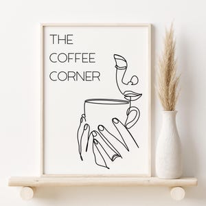以下が含まれることがあります： コーヒーカップからコーヒーを飲む人の白黒線画プリント。プリントの上部に「THE COFFEE CORNER」の文字があります。