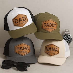 May include: Four baseball caps with different colors and designs. Each cap has a brown leather patch with a different title: "Dad", "Daddy", "Papa", and "Nana".