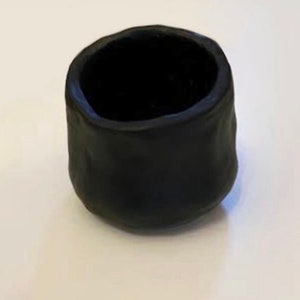 Pu&ograve; includere: Un piccolo vaso in ceramica nera con una superficie ruvida e testurizzata. Il vaso &egrave; vuoto e ha una forma arrotondata.