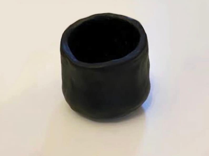 Pu&ograve; includere: Un piccolo vaso in ceramica nera con una superficie ruvida e testurizzata. Il vaso &egrave; vuoto e ha una forma arrotondata.