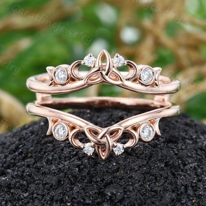 May include: Rose gold ring enhancer with a Celtic knot design and small round diamonds. The enhancer is designed to fit around a solitaire engagement ring.