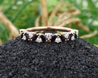 May include: A rose gold band with a marquise-shaped black diamond and round white diamonds set in a pave setting.