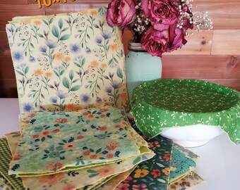 May include: A stack of colorful beeswax food wraps with floral patterns. The wraps are available in two sizes: 8x8 inches and 10x10 inches. A 4-pack of wraps is available for $20, including two small and two large wraps.