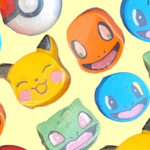 Puede incluir: Surtido de bombas de baño coloridas con forma de personajes. Incluye un Pikachu amarillo, un Charmander naranja, un Squirtle azul, un Bulbasaur verde y una Pokéball roja y blanca. Cada bomba de baño está envuelta individualmente sobre un fondo amarillo.