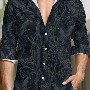 Peut inclure: Chemise sombre à boutons avec un motif de corbeaux noirs et de branches d'arbres. La chemise à manches longues a une bordure blanche sur les poignets et le col. La chemise est boutonnée sur le devant.